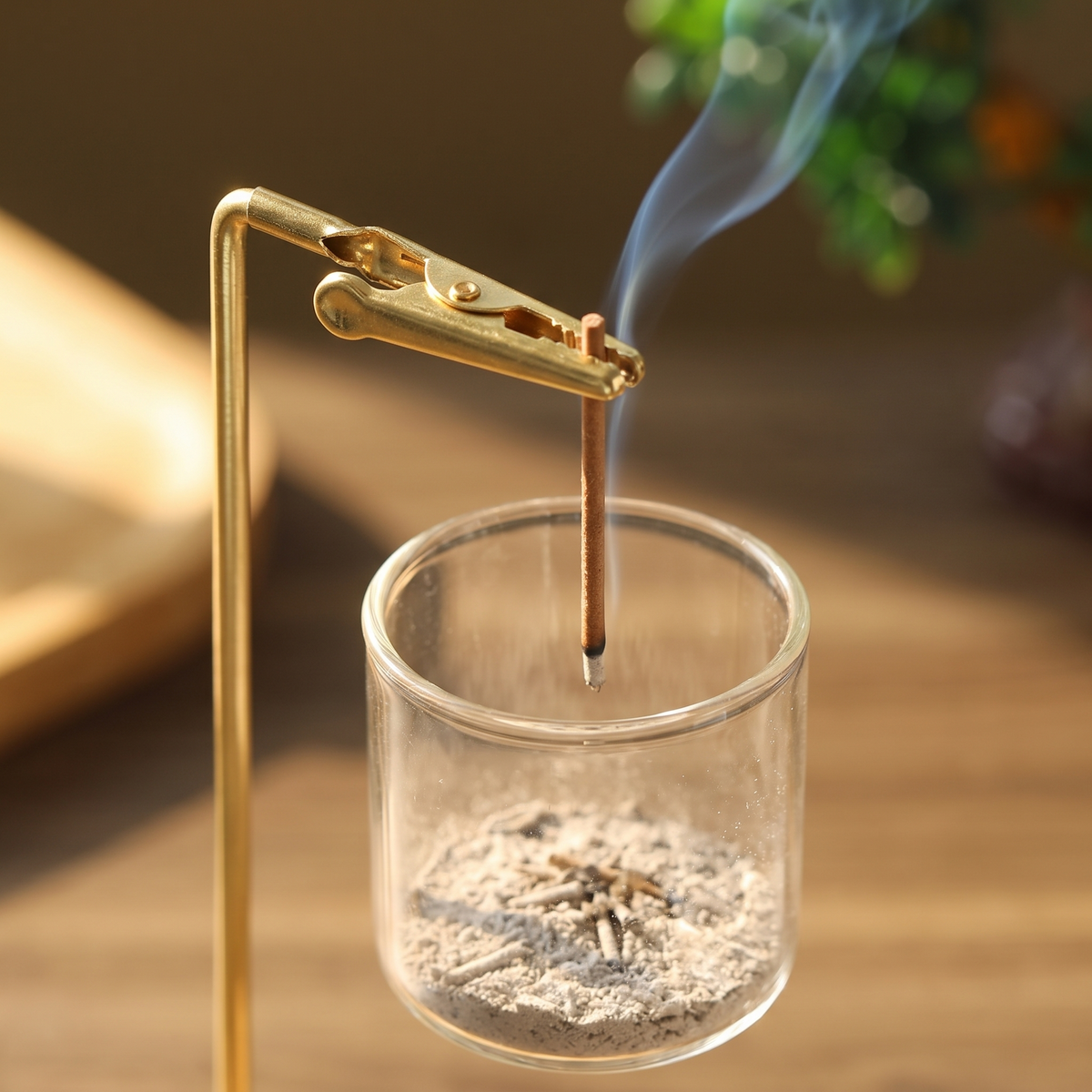 Ash falling from the clipped stick into the glass cup