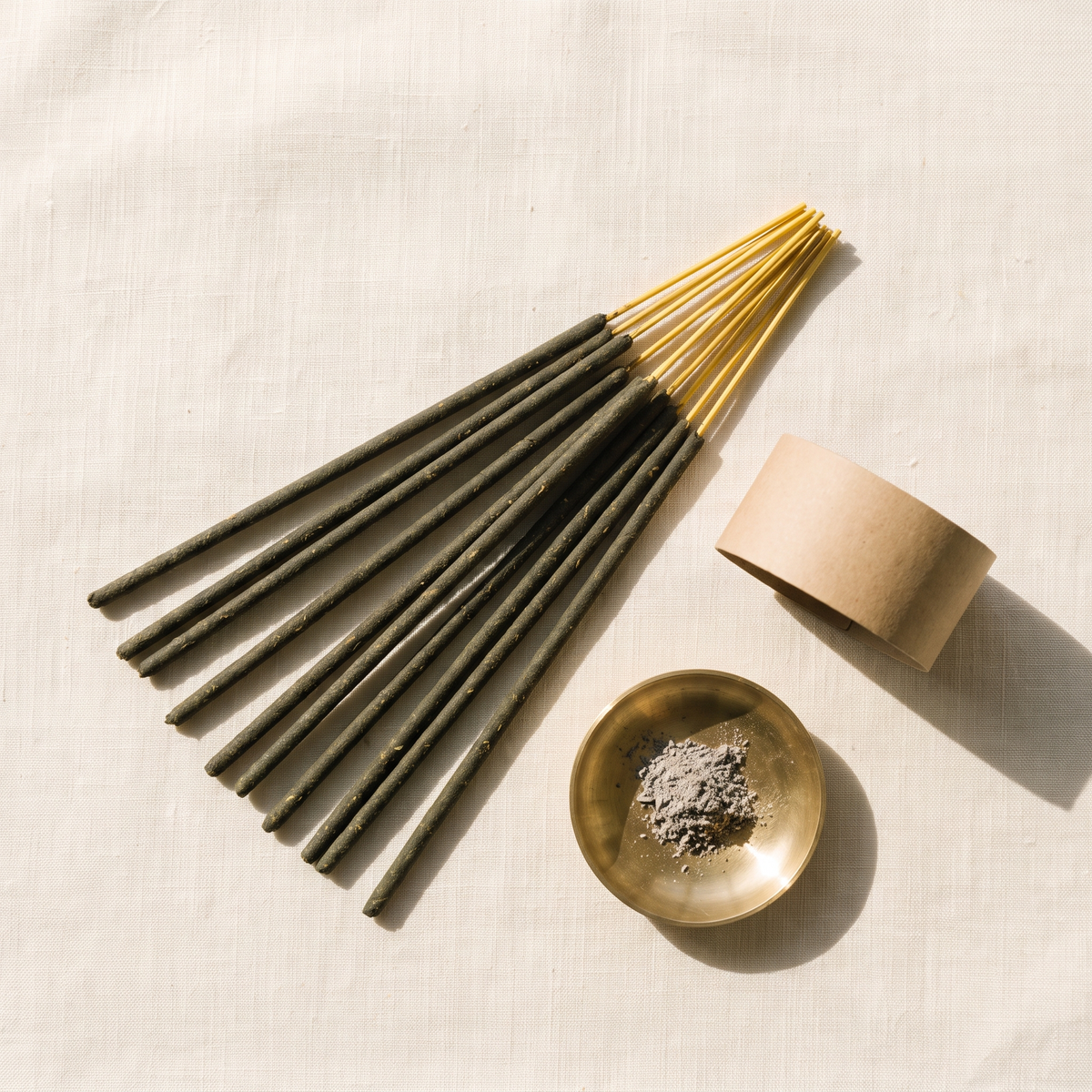 Hand-rolled incense sticks fanned beside a brass ash dish