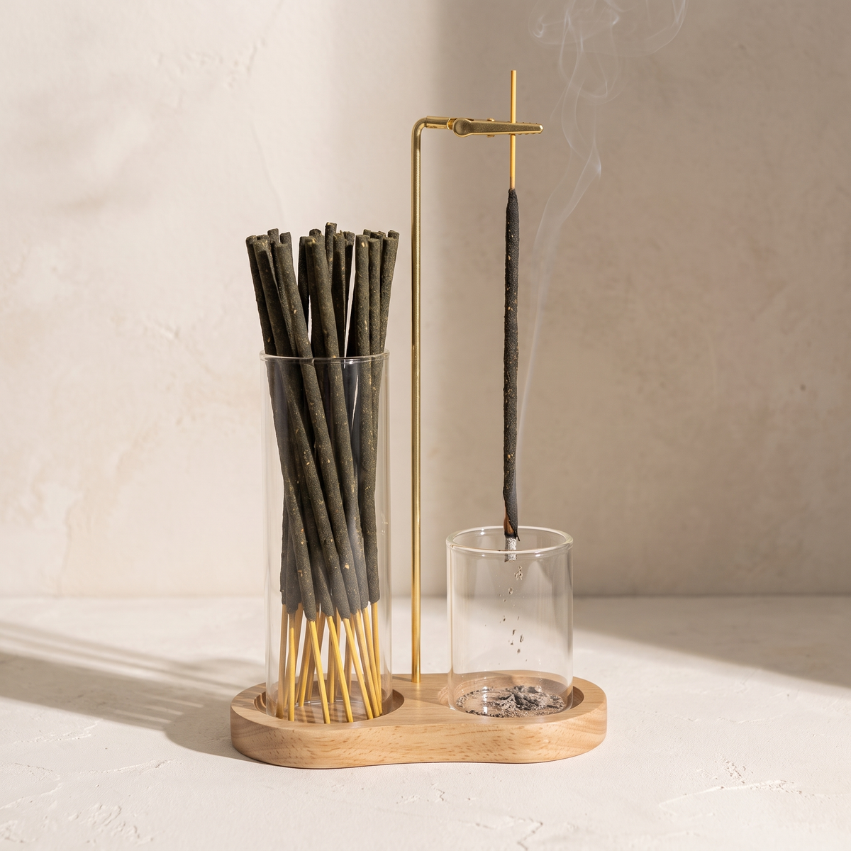 The sticks stored in the Kodo Burner's tall glass tube, one burning in the clip