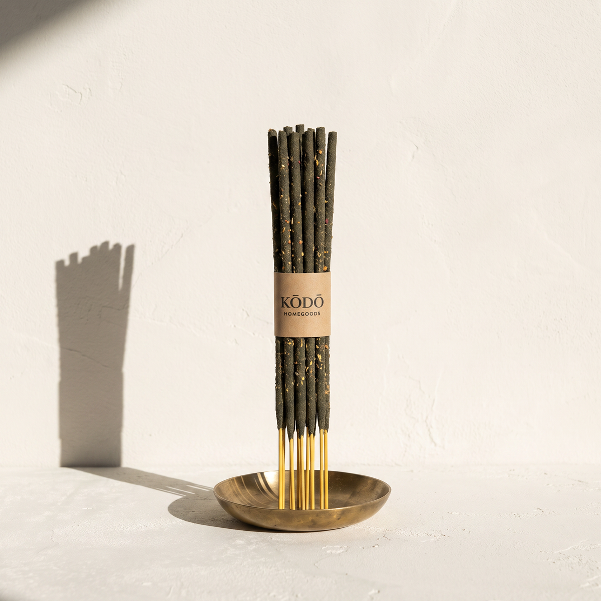 Kodo-banded bundle of slim hand-rolled Nag Champa sticks in a brass dish