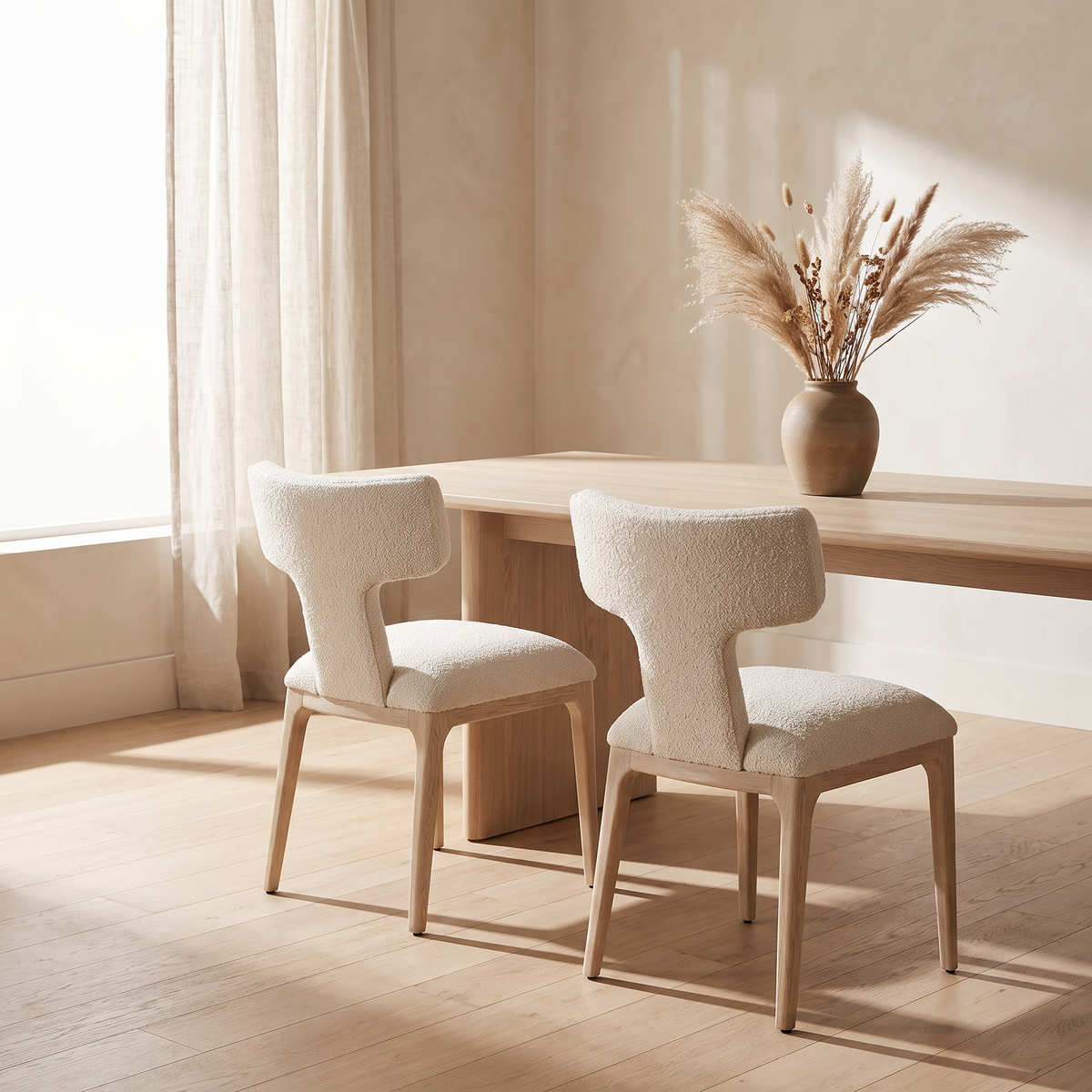 Two boucle wingback dining chairs at an oak table