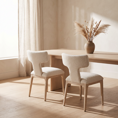 Two boucle wingback dining chairs at an oak table