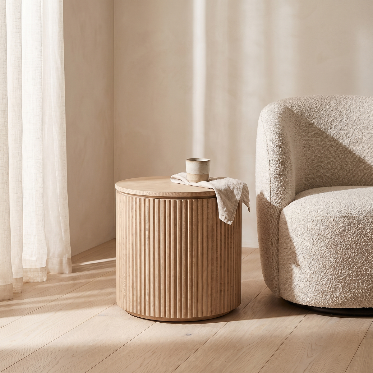 Fluted drum side table beside a boucle armchair