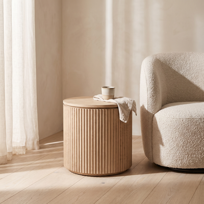 Fluted drum side table beside a boucle armchair
