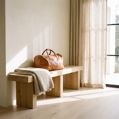 Leather duffle on a pale oak bench in an entryway