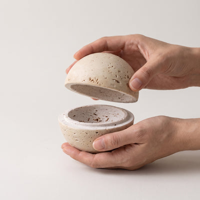 Hands lifting the domed top away from the bowl, showing scale