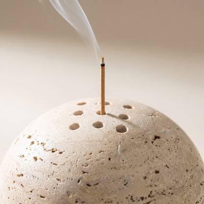 An incense stick standing in one of the drilled holes, smoke rising