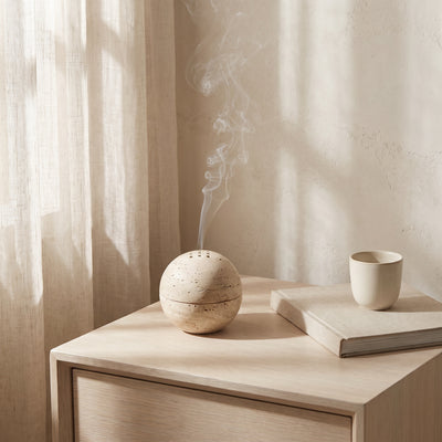The Stone Burner on a pale oak nightstand, smoke rising
